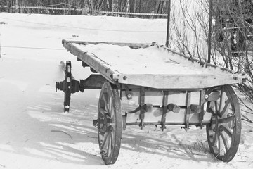 Fototapeta na wymiar Black and white image of an old wooden cart in the snow. Rear view