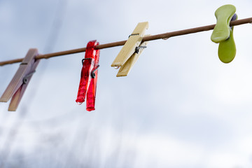 Wäscheklammern in zarten Pastell Farben und eine Klammer in leuchtendem Rot im Regen an nasser...