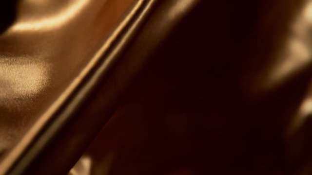 Golden wavy fabric background in super slow motion, 4K