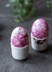 Colorful eggs in egg-cup on black background