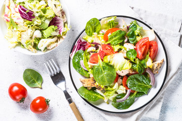 Green salad with chicken and vegetables on white.