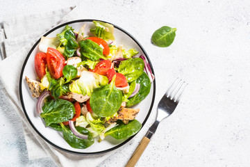 Green salad with chicken and vegetables on white.