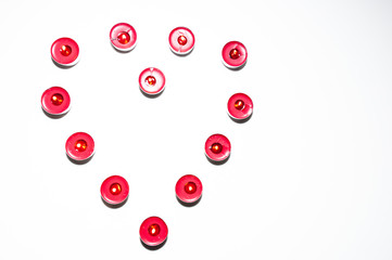Heart made of candles on blank, white background. Symbol of love made of red burning candles isolated