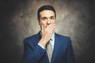 Funny businessman is covering his mouth with hands