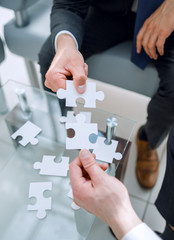 close up.pieces of the puzzle in the hands of business partners