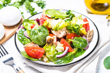 Green salad with chicken and vegetables on white.