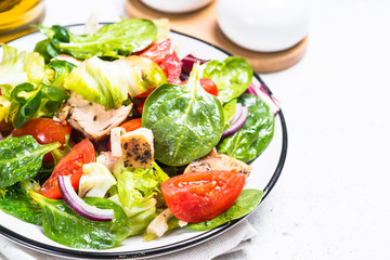 Green salad with chicken and vegetables on white.