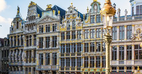 Fototapeta premium Vintage street lamp in front of rich sculptural decorated guild houses facades on The Grand Place of Brussels, Belgium. Lavishly designed gables are based on Italian Baroque with Flemish influences.
