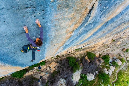 A climber tries hard high up on a cliff.