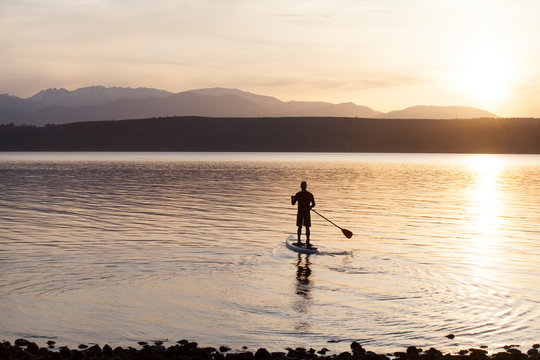 A male paddles his stand up paddle board on the Puget Sound near Poulsbo, Washington. 