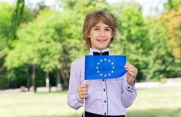 Portrait of happy schoolboy with flag of European Union on school background. Education, study abroad. School vacation in Europe.