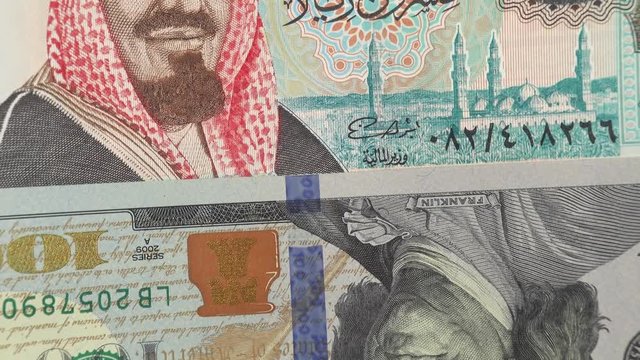 Saudi Arabia riyal against US dollar bill rotating. Saudi Arabia and USA trade, economy. 4K stock video footage