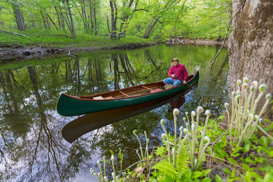 A man canoeing in spring on the Lamprey River in Epping, New Hampshire.