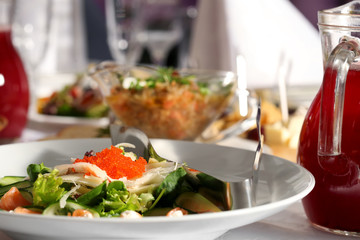 Salad of fish, caviar and cucumber in a white plate