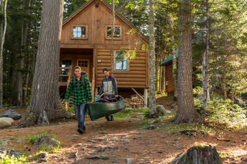 Two Men Carry A Canoe Past The Cabins At The Lodge Near Greenville, Maine