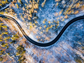 Winding road through the forest, from high mountain pass, in winter time. Aerial view by drone . Romania