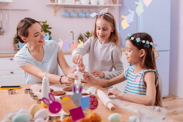 Positive delighted girls helping their mother in baking