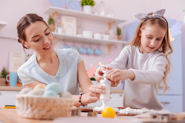 Pleased young female person helping her daughter