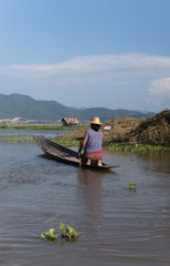 woman paddling on a small wooden boat on inle lake in myanmar