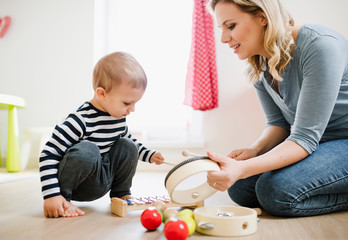 Mother and toddler son playing with musical instruments at home