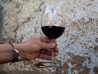 A man handcuffed to a glass of red wine. Alcohol addiction or alcoholism concept