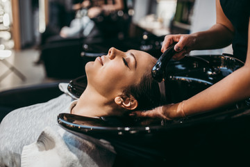 Beautiful young woman getting a hair wash. Hair salon styling concept.
