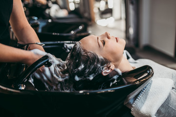 Beautiful young woman getting a hair wash. Hair salon styling concept. - obrazy, fototapety, plakaty
