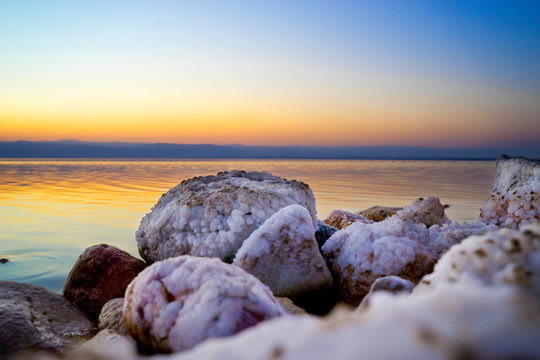 Salt-covered rocks on shore of Dead Sea at sunset, Madaba Governorate, Jordan