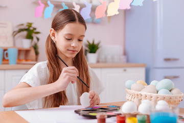 Attentive longhaired brunette girl painting boiled eggs
