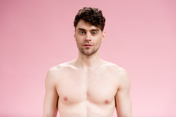 serious and confident brunette man looking at camera on pink