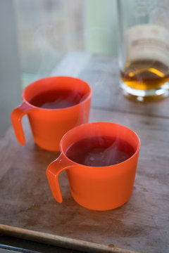 Hot Apple Cider With Bourbon In Orange Cups Inside The Pickett Butte Fire Lookout Near Tiller, Oregon, USA