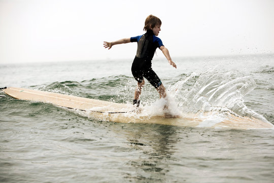 A young boy rides a wave on a surfboard