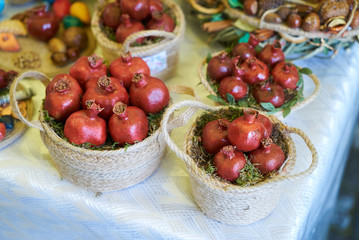 Dry red pomegranate fruit in wicker basket on table