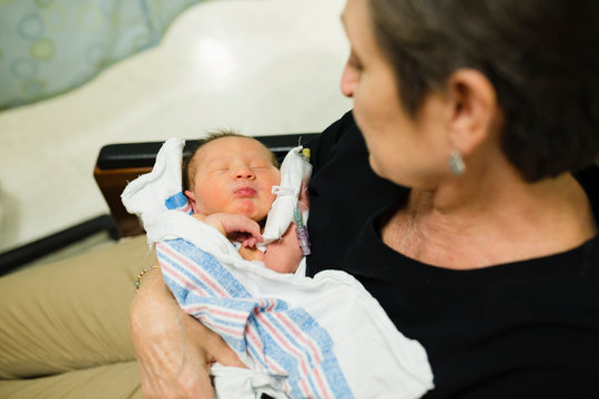Grandma holds newborn baby grandchild in hospital room