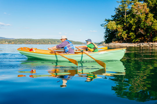 A Man With His Son And Their Dog In A Rowing Boat In Deer Harbor, Orcas Island, Washington, Usa