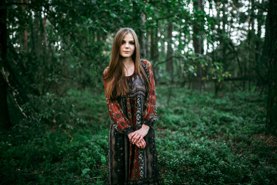 girl stands in the forest in a long dress