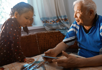 Senior man and his granddaughter learning how to use tablet computer