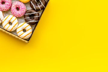 Modern design with donuts in box on yellow background top view space for text
