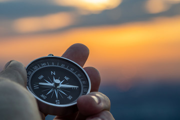 compass in hand with sunset sky on the background - obrazy, fototapety, plakaty