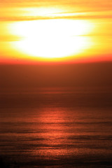 Fototapeta premium The orange sunset reflected in the small waves. The shimmering waves in the sunset