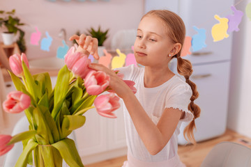 Attentive blonde girl enjoying fresh bouquet of tulips