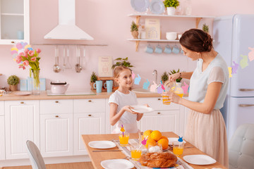 Charming mom and daughter laying the table