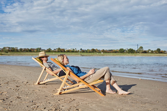 Young couple in deckchairs relaxing at the riverbank