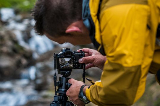 An outdoor photographer thaking photos under the rain in Devero National Park, Ossola, Italy.
