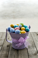 Easter eggs collected in a purple bucket with ribbon around