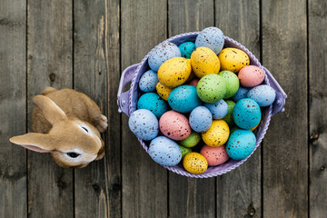 Colorful Easter eggs with bunny on wooden table in spring time, top view