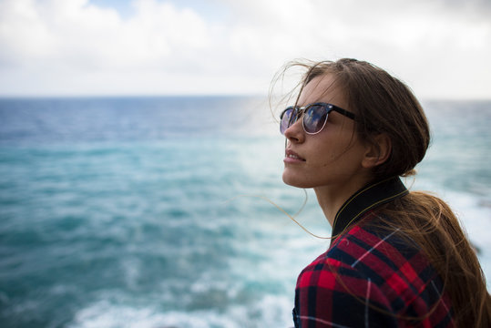 Portrait of woman with brown hair and sunglasses against sea, Sardinia, Italy