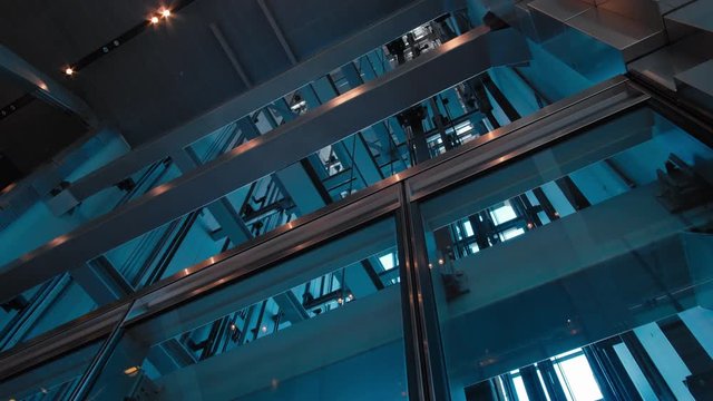 Futuristic Low Angle Shot with Nice Geometry of Elevators in Modern Office Business Building Moving Up in Transparent Glass Lift Shaft in Skyscraper