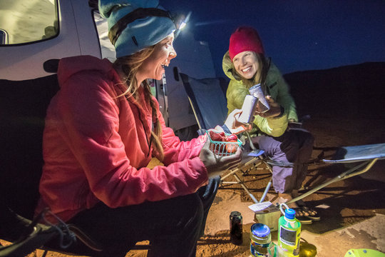 Two women eating while camping in desert, Hole in the Rock Road, Utah, USA