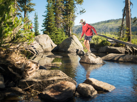 Young boy jumping off a rock on a parkour style obstacle course made by nature